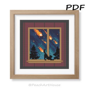 May include: Cross-stitch art of a night scene with a window view. The window shows a dark blue sky with falling orange meteorites above silhouetted trees. The artwork is framed in a light brown wooden frame. Text in the upper right corner reads "PDF".