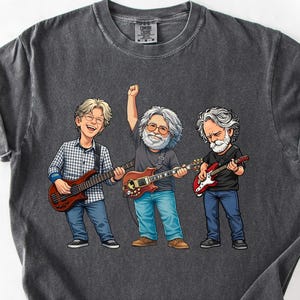 May include: Dark gray t-shirt featuring a cartoon illustration of three musicians playing guitars. The illustration includes the text "Pepper" in a banner at the top. The musicians are depicted with guitars and wearing casual clothing.