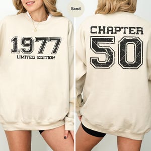 May include: A sand-colored crewneck sweatshirt featuring black distressed-style text. The front displays 1977 LIMITED EDITION, while the back features the text CHAPTER 50 with large numbers. The design uses a bold, block-style font throughout.