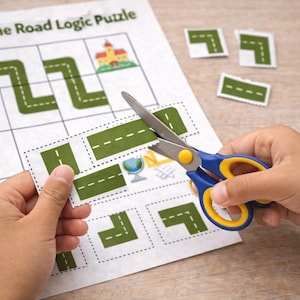 Puede incluir: Unas tijeras azules y amarillas cortan piezas de rompecabezas de carretera de una hoja impresa. La hoja tiene una cuadrícula con un mapa de carreteras y el texto "Build the Road Logic Puzzle".