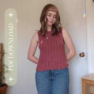 Peut inclure: Un haut sans manches en crochet rose poussiéreux avec un motif texturé. Le haut a une encolure haute et est associé à un jean bleu. Une petite épingle arc-en-ciel est visible sur le côté gauche. Le texte "PDF DOWNLOAD" est sur le côté gauche de l'image.