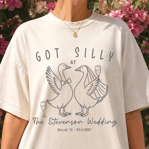 May include: Cream-colored t-shirt with the text "GOT SILLY at The Stevenson Wedding" and the date 09.14.2027. The graphic features two geese, one with a bow tie and the other with a veil, holding champagne glasses. The shirt is a wedding-themed item.