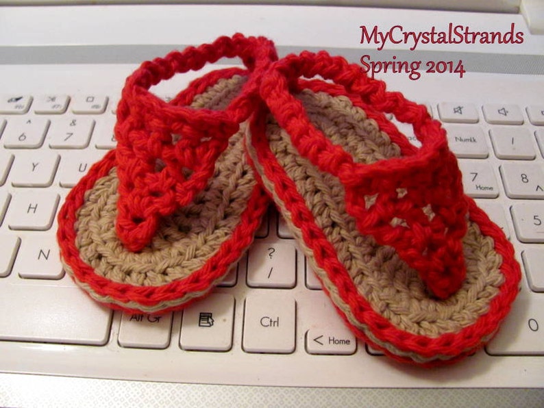 May include: A pair of red and beige crocheted flip-flops. The flip-flops are on a white laptop keyboard. The text "MyCrystalStrands Spring 2014" is visible in the upper right corner of the image.