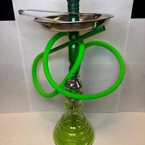 May include: A green hookah with a glass base and a metal tray. The hookah has a green hose and a silver metal handle. A pair of silver tongs rests on the tray.