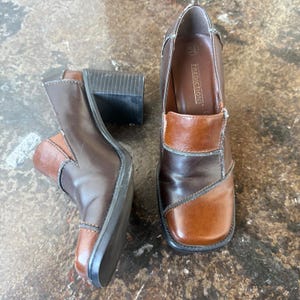 May include: Brown leather ankle boots with a square toe and block heel. The boots feature a two-tone design with lighter brown accents and the brand name "PREDICTIONS" visible inside one shoe.