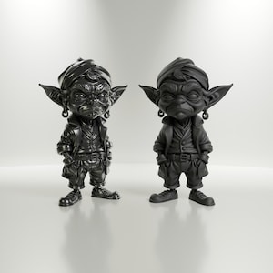 Puede incluir: Dos figuras negras de resina de un personaje estilizado que lleva un turbante, una chaqueta y pantalones cortos. Las figuras tienen orejas grandes, pendientes y posan con las manos en los bolsillos. Las figuras están sobre una superficie blanca.