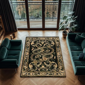 May include: A rectangular rug with a dark green background and a gold and cream-coloured ornate design. The rug features a central image of a serpent surrounded by floral and scrollwork patterns. The rug is placed on a hardwood floor.