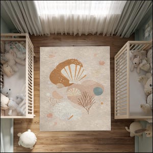 May include: A beige area rug with an abstract design featuring seashell and coral-like shapes in shades of brown, pink, and blue. The rug is placed on a wooden floor, with two cribs on either side, creating a nursery setting.
