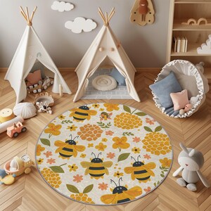 May include: A round rug with a bee and flower pattern. The rug features a cream background with yellow, orange, and black bees and flowers. Two small teepee tents are in the background, along with other children's toys.