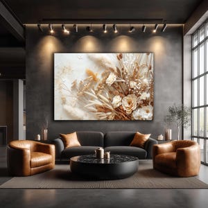 Op de afbeelding: Een groot canvas kunstwerk met een gedetailleerd bloemstuk in neutrale tinten crème, beige en bruin. Het kunstwerk wordt getoond boven een donkergrijze bank en twee bruine leren fauteuils in een moderne woonkamer.