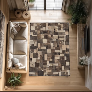 May include: Overhead view of a living room with a large rectangular rug. The rug features a mosaic pattern of various shades of brown and gray, resembling stone tiles. The room includes a beige sofa, wooden flooring, and a large window.