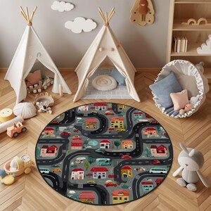 May include: A round gray rug with a road and town design. The rug features winding black roads, colorful houses, and various vehicles. Two white teepee tents are in the background, along with other children's toys.
