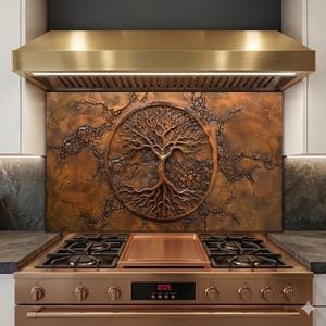 Puede incluir: Salpicadero de cocina de tono cobre con un diseño de árbol de la vida, colocado sobre una encimera de gas. El árbol está centrado dentro de un marco circular, con detalles intrincados de ramas y raíces. La campana extractora es dorada.
