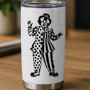 Puede incluir: Un vaso de acero inoxidable blanco con tapa de pl&aacute;stico transparente, que presenta un estampado gr&aacute;fico negro de un payaso con sombrero y un traje con un lado de lunares y el otro a rayas, de pie con los brazos extendidos.