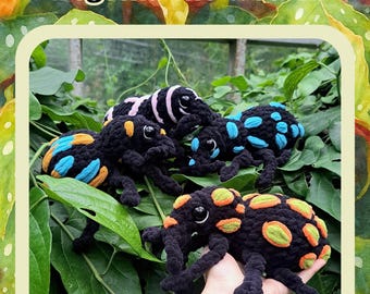 May include: A PDF crochet pattern titled Begonia the weevil featuring three plush weevil toys. Each toy is black with distinct coloured spots: one with pink, one with blue, and one with orange and green. The toys have large black eyes and long snouts.