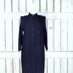 Può includere: Un abito lungo a maniche lunghe a righe nere e rosa con colletto alla coreana e chiusura con bottoni.