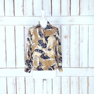 May include: A long-sleeved blouse with a brown, black, and white abstract print. The blouse has a collared neckline and a button closure.