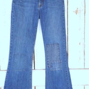 Könnte beinhalten: Blaue Jeans mit Schlag und Patches auf den Knien.