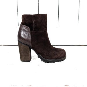 May include: Brown suede ankle boots with a chunky heel and a contrasting brown leather panel on the side.
