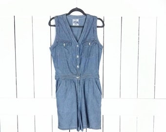 Op de afbeelding: Een lichtblauwe denim jumpsuit met een knoopsluiting aan de voorkant, zonder mouwen en twee zakken aan de voorkant.