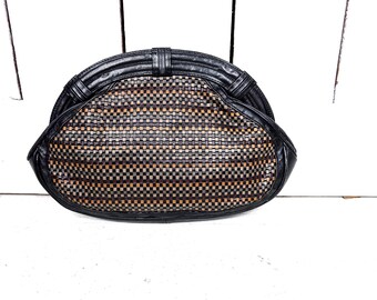 May include: A black and brown woven clutch bag with a rounded shape and a flap closure.