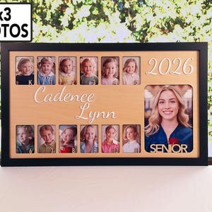 May include: Black framed photo display for 2x3 photos. The display features a light wood-colored center with the name "Cadence Lynn" and the year "2026" in a decorative font. It includes spaces for multiple photos and a larger photo with the word "SENIOR".