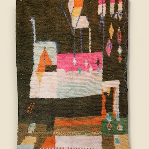 May include: Hand-woven rug with a dark green background and a colorful abstract design. The rug features geometric shapes in orange, pink, white, and blue. The bottom edge has a fringe.