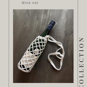 May include: A white, crocheted wine net holds a green wine bottle with a blue and white label. The net has a diamond pattern and a long, looped handle. The text "CABRI" and "Wine net" are at the top, with "@CRAFTYCABRI" at the bottom.