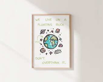 May include: A framed print with the text "WE LIVE ON A FLOATING ROCK YOU DON'T OVERTHINK IT." The artwork features a hand-drawn style illustration of Earth, planets, stars, and a cloud, all in bright colors.