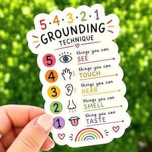 May include: A white sticker with the text "5-4-3-2-1 GROUNDING TECHNIQUE" in colorful lettering. The sticker lists the five senses with corresponding icons: eye, hand, ear, nose, and tongue. A rainbow and hearts are at the bottom.