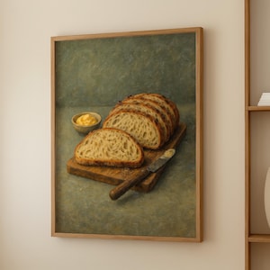 Puede incluir: Pintura enmarcada que representa una naturaleza muerta de pan rebanado sobre una tabla de cortar de madera, un cuchillo y un cuenco pequeño con mantequilla. El pan es de color marrón dorado y la mantequilla es amarilla. El fondo es verde apagado.