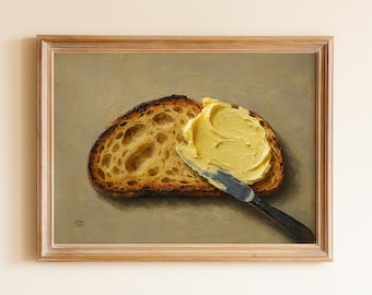 May include: A framed painting shows a slice of toasted bread with butter being spread. The bread has a dark crust and a textured interior. The butter is a bright yellow, and a knife with a black handle is used to spread it.