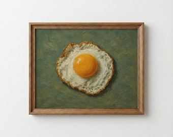 May include: A framed painting depicting a fried egg. The yolk is a vibrant orange, encircled by a white egg white with a lightly browned border. The background is a muted green, and the frame is a warm brown.