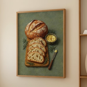 May include: A framed print of a loaf of bread, sliced bread, butter, and a knife on a wooden cutting board. The bread is golden brown with a textured crust. The butter is in a small bowl. Rosemary sprigs are scattered around the food.