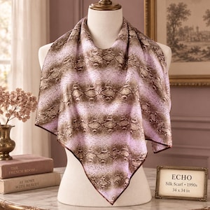 May include: A square silk scarf featuring a brown and tan snakeskin pattern layered over a light pink background. The scarf is displayed on a mannequin and includes a small sign that reads ECHO Silk Scarf 1990s 34 x 34 in.