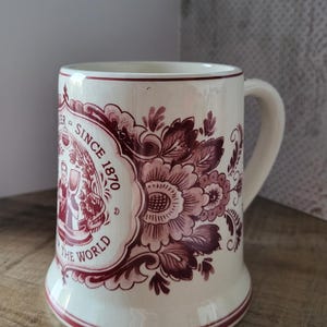 May include: A set of three ceramic mugs with a speckled, matte finish. The mugs are in shades of cream, light brown, and dark brown. Each mug has a simple, minimalist design and a rounded handle.