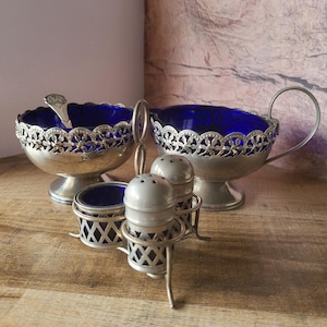 Könnte beinhalten: Eine weiße Keramik-Tasse mit schwarzem Henkel und dem Text "But First, Coffee" in schwarzer, handschriftlicher Schrift. Die Tasse steht auf einer weißen Oberfläche.