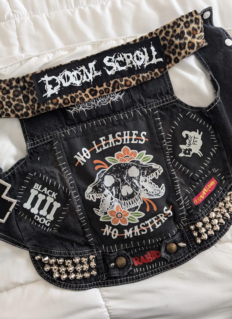 May include: Black denim vest with patches, studs, and a leopard print belt. The patches say "Doom Scroll", "No Leashes No Masters", "Black Dog", "Rabid", and "Dog S**t Queen".