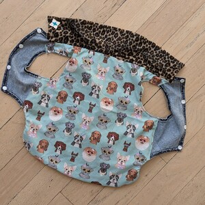 May include: A blue denim and leopard print dog car seat cover with a pattern of dogs wearing sunglasses on a light blue background.