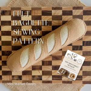Op de afbeelding: Een beige en crèmekleurig vilt baguette speelgoed met zichtbare stiksels, diagonaal geplaatst. De tekst op de afbeelding luidt: FELT BAGUETTE SEWING PATTERN, Mini Market Goods en THE MINI MARKET METHOD, met kleine illustraties van naaigereedschap.
