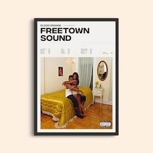 May include: Album cover art for "Freetown Sound" by Blood Orange. A couple are embracing on a yellow bed in a bedroom. The album title is in bold white text on a black background.