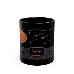 Puede incluir: Taza de cerámica negra con una escena espacial pixelada. El diseño incluye un planeta, estrellas fugaces y un panel de control de nave espacial. La taza es cilíndrica y tiene un acabado brillante.