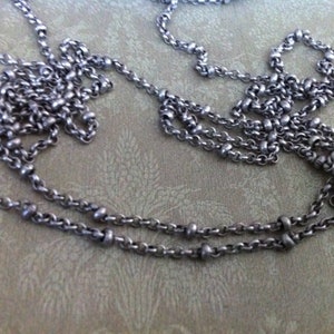 May include: A silver chain necklace with small round beads. The chain is layered and appears to be made of metal.