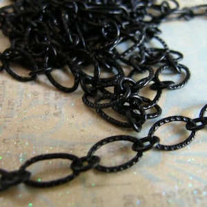 May include: Black chain with oval links. The chain is made of metal and has a matte finish.