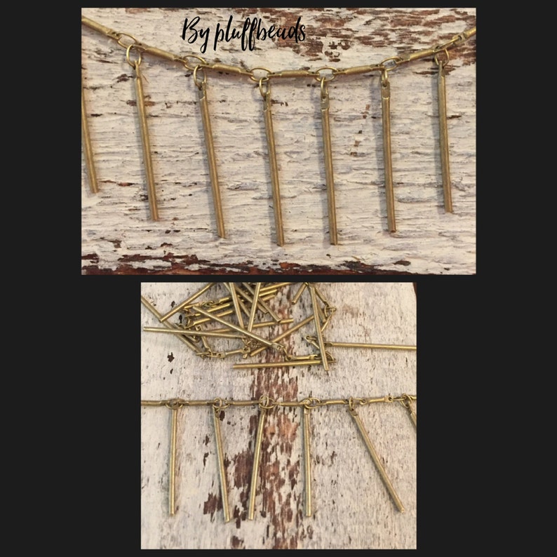 May include: A gold chain necklace with multiple gold metal bar pendants hanging from it. The necklace is displayed on a wooden surface. "By fluffbeads" is written on the surface.