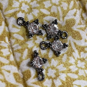 May include: Four silver-toned metal charms with clear crystal accents. Each charm has a loop for attaching to a necklace, bracelet, or other jewelry.