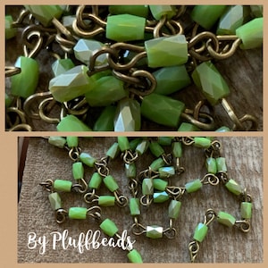 May include: Close-up of a necklace featuring faceted, light green beads strung together with antique brass-colored metal links. The beads have a geometric shape and are arranged in a repeating pattern. The text "By Pluffbeads" is at the bottom of the image.