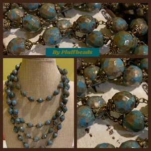 May include: Multi-strand necklace featuring turquoise blue and gold beads. The necklace is made of multiple strands of beads, with each strand having a different length. The beads are a mix of turquoise blue and gold, and they are all faceted. The necklace is a beautiful and unique piece of jewelry.