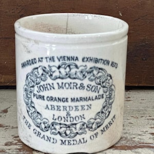 May include: White ceramic jar with a black and white label that reads "AWARDED AT THE VIENNA EXHIBITION 1873 JOHN MOIR & SON PURE ORANGE MARMALADE ABERDEEN & LONDON THE GRAND MEDAL OF MERIT"