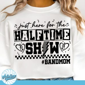 May include: White sweatshirt with the text "just here for the HALFTIME SHOW #BANDMOM" in black. The design includes musical notes, a lightning bolt, and a heart-shaped treble clef. The sweatshirt is a casual, comfortable style.